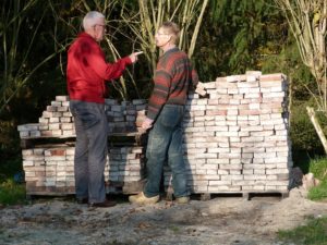 7. Dick Somsen van de Historische Kring Eibergen en eigenaar Groot Wassink van camping De Vlierhof bij twee stapels oude stenen voor hergebruik.
